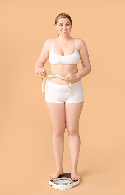 Overweight woman standing on scales against color background.