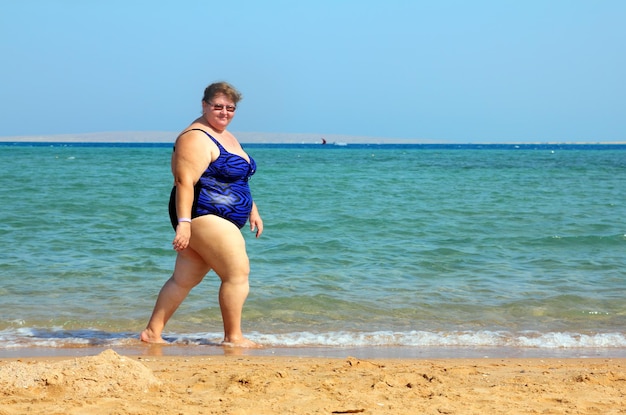 Photo overweight woman walking on sea beach