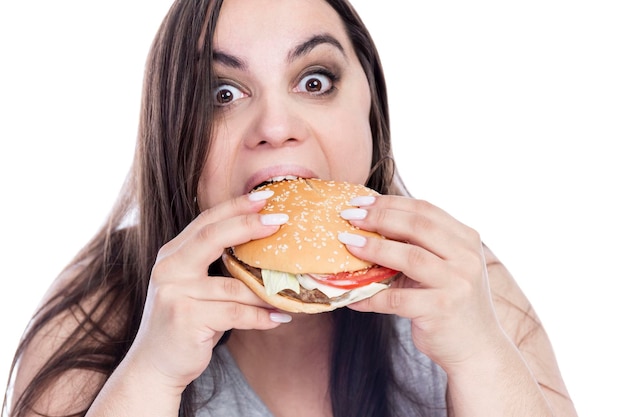 写真 食欲のある太りすぎの女性は貪欲にハンバーガーを食べる肥満とファーストフード分離された白い背景のクローズ アップ