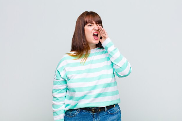 Photo overweight woman yelling loudly and angrily to  on the side, with hand next to mouth