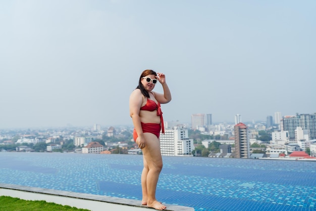 Overweight young asian woman wearing swimsuit relaxing in the pool Happy plus size woman cheery funny Vacation Traveling in summer