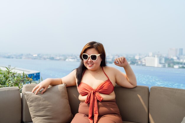 Photo overweight young asian woman wearing swimsuit relaxing in the pool happy plus size woman cheery funny vacation traveling in summer