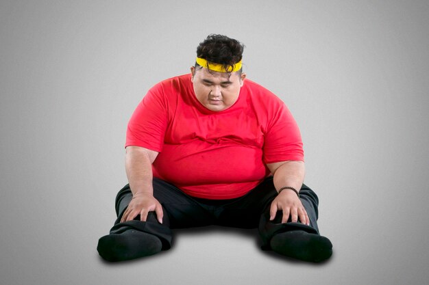 Photo overweight young man sitting against gray background