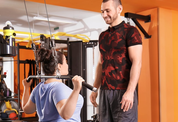 Overweight young woman with trainer in gym