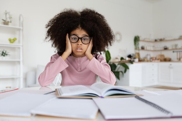 Overweldigd Afrikaans-Amerikaans schoolmeisje dat huiswerk maakt