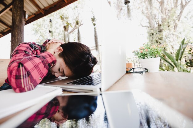 Overwerkte en vermoeide jonge vrouw slapen op bureau