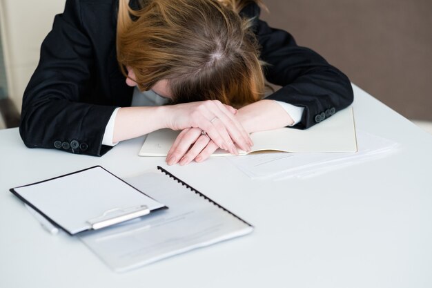 Overwerkte en vermoeide zakenvrouw liggend op het bureau