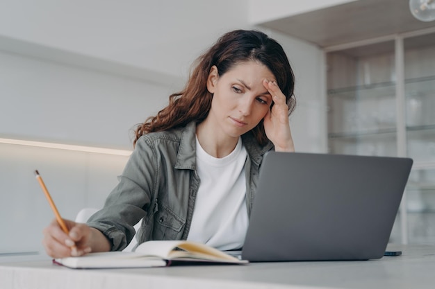 Overwerkte Spaanse dame heeft hoofdpijn Ziek vermoeide freelancer werkt thuis op laptop