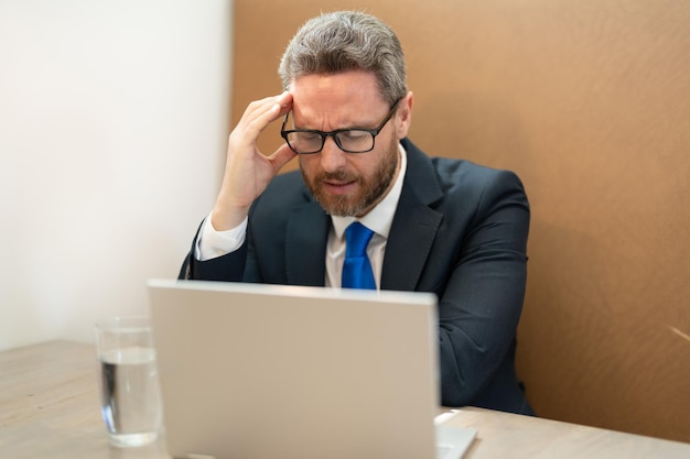 Overwerkte zakenman heeft hoofdpijn op kantoor Overwerkte zakenman heeft hoofdpijn