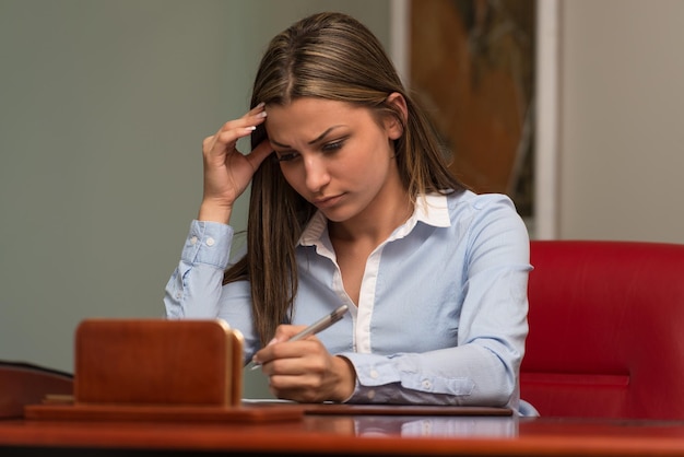 Overwerkte zakenvrouw die bij haar bureau zit