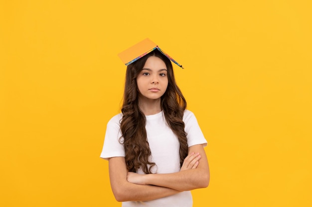 Overwhelmed intellectual child back to school education get smart serious pupil with copybook on head girl with grammar book bookish kid in book store student has much work