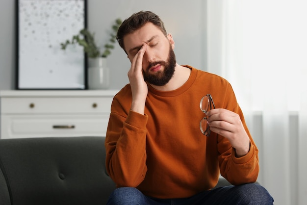 眼鏡をかけた圧倒された男が自宅で苦しんでいる