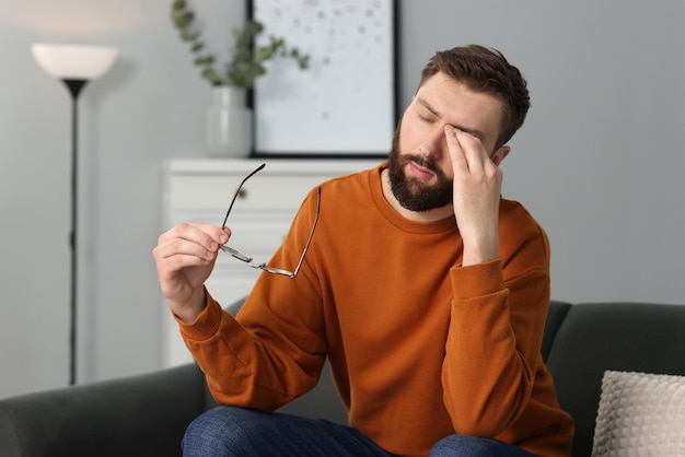 眼鏡をかけた圧倒された男が自宅で苦しんでいる
