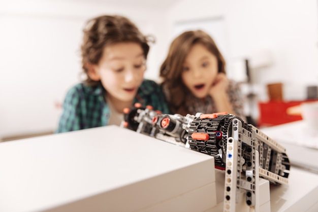 Overwhelming emotions inside us. Shocked surprised emotional kids sitting in the science classroom and looking at robot while having tech class