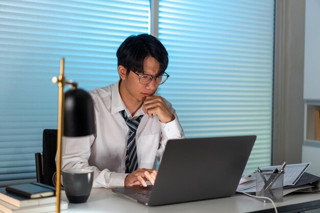 Overwork Concept The male who is wearing glasses resting his chin on his right hand