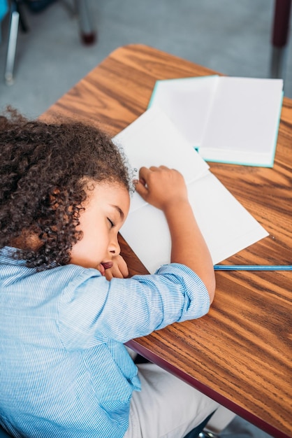 Photo overworked african american schoolgirl sleeping on desk