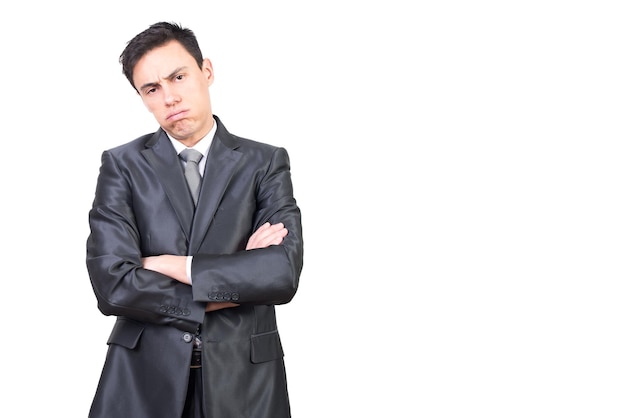 Overworked bored young male manager with dark hair in formal outfit exhaling and looking at camera while standing against white background with crossed arms