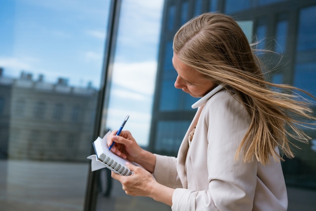 Donna d'affari oberata di lavoro donna d'affari multitasking che parla al cellulare con una giacca leggera ne...