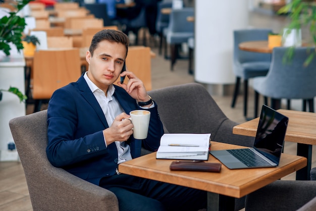 Overworked businessman have coffee break and speaking on smartphone