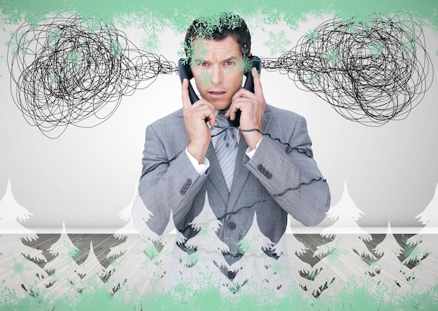 Photo overworked businessman holding two telephones against green snowflake design