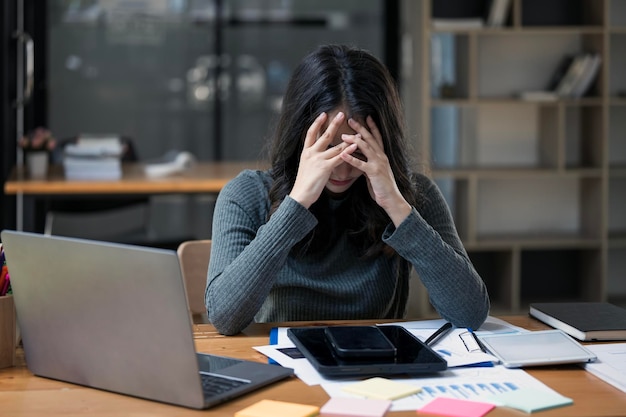 Overworked and frustrated young woman in front of computer in office tired business woman