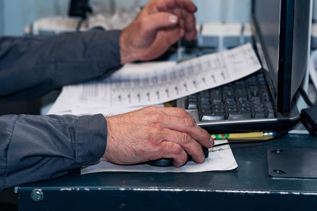 Overworked hands of an age worker at a computer controlling the\
production process