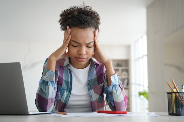 Photo overworked pupil is studying remote at home and getting headache schoolgirl is tired from homework