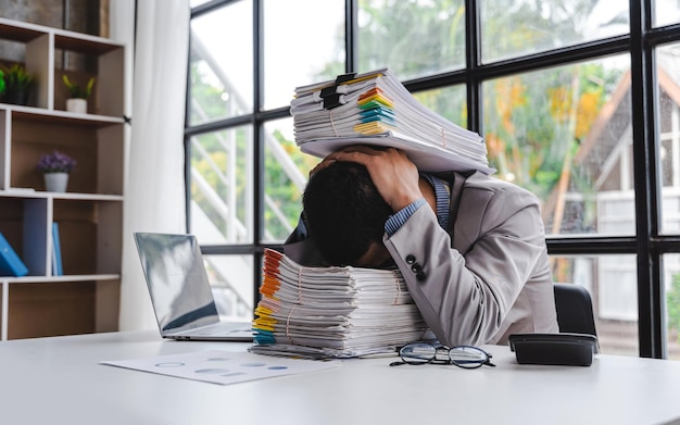 Overworked sad businessman with stack of papers business people deadline stress and paperwork concept