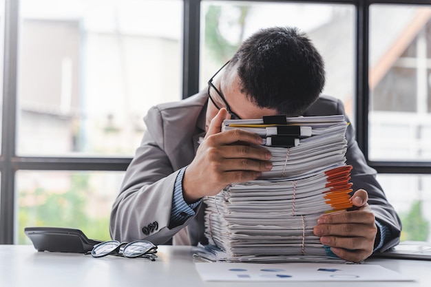 Overworked sad businessman with stack of papers business people deadline stress and paperwork concept