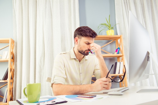 Overworked tired young man sitting in office and thinking