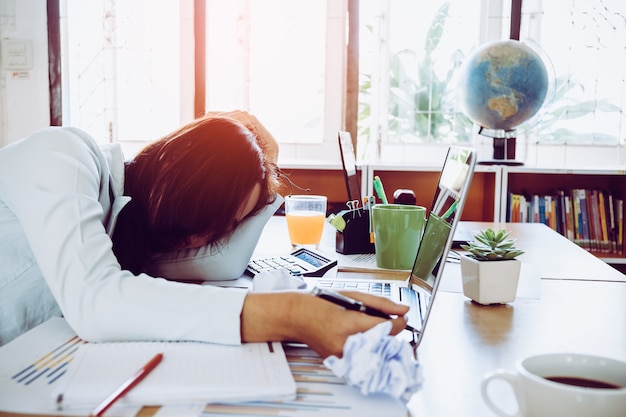 Overworked and tired young woman sleeping on desk