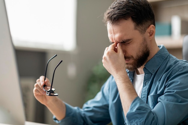 Overworking concept businessman taking off glasses and massaging nose bridge