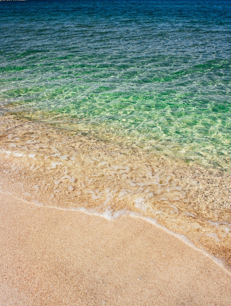 Overzeese golven van blauw transparant water op zandig strand