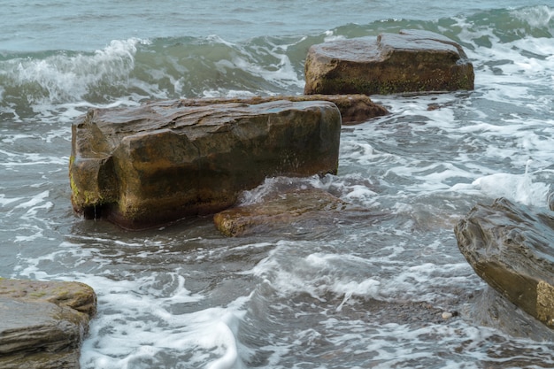 Overzeese rotsen in het strand in kust.