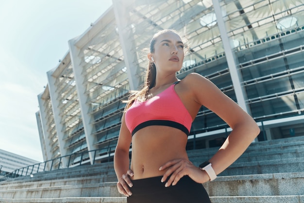 ow angle view of confident young woman in sportswear holding hand on hip