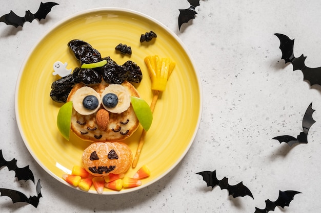 ハロウィーンの子供の朝食のための果物とフクロウのパンケーキ