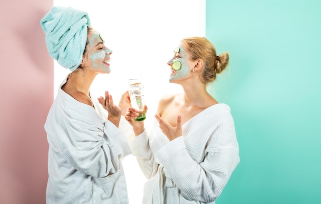 Own spa salon at home. conception of skin care by using white mask and cucumbers on the face. two female sisters have weekend