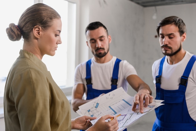 Foto un proprietario di un appartamento parla con i costruttori e considera lo schema della casa