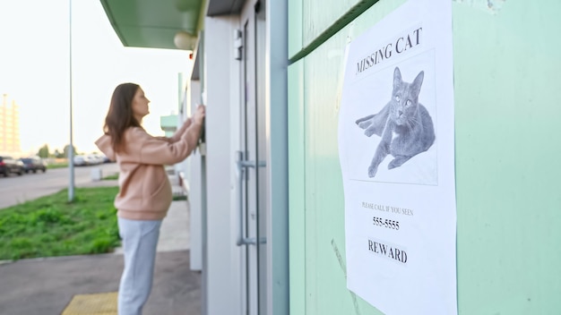 Il proprietario in felpa con cappuccio appende poster del gatto scomparso sull'edificio