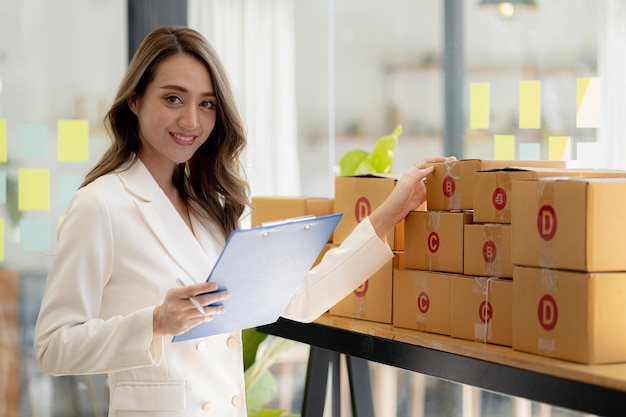 The owner of an online store is checking orders for packaged products in order to prepare them for delivery to customers as ordered through the website Online selling and online shopping concepts