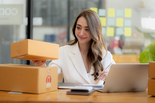 The owner of an online store is checking orders for packaged products in order to prepare them for delivery to customers as ordered through the website Online selling and online shopping concepts