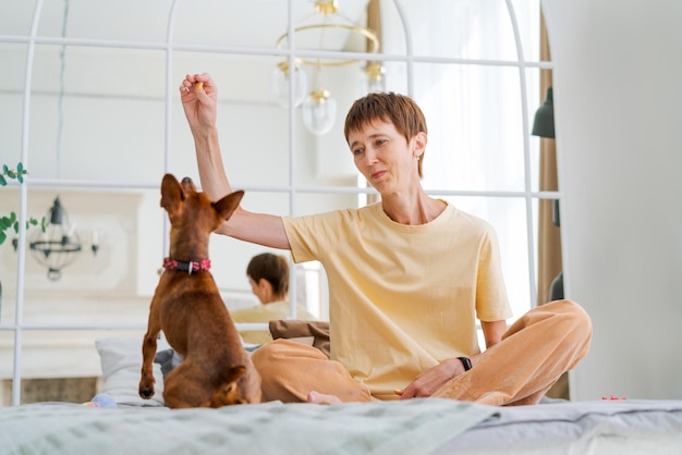 Владелец играет с радостной собакой дома счастливая зрелая женщина наслаждается упражнениями