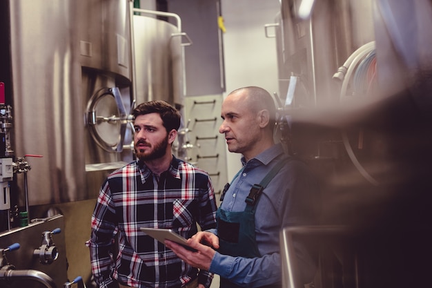 Owner and worker examining machinery