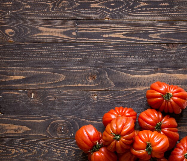 Ox heart tomatoes, on rustic wood background, free space for text.