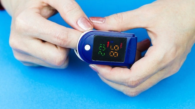 Oximeter on the finger of a woman's hand, reading oxygen in human blood.