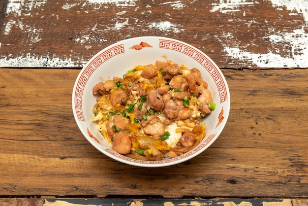 Photo oyakodon a japanese donburi made by simmering chicken egg chives and other ingredients together in a sauce then serving over a large bowl of rice