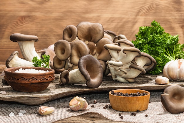 Oyster mushrooms ready for cooking Fresh parsley spices and garlic Trendy hard light dark shadows old wooden background copy space