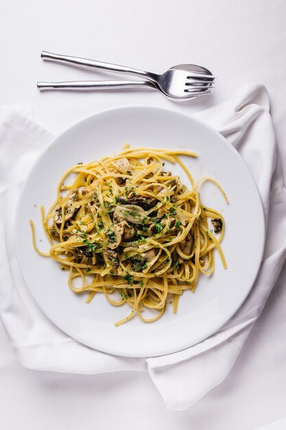 Oyster spaghetti served in white plate on white tablecloth