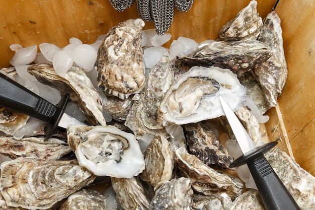 Oysters shells and a knife in a basket on ice