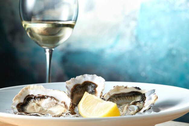 Oysters in a white plate with lemon and a glass of wine